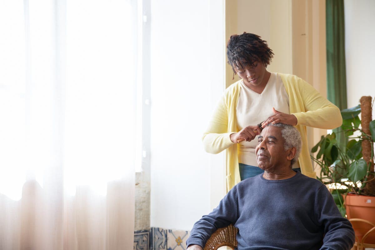 Caregiver gently combing and grooming an elderly person's hair at home